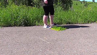 Golden shower watering flowers in a park. Chubby milf with big ass and hairy pussy pisses outdoors